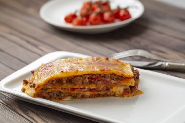 Beyaz tabakta servis edilen peynirle kaplı lezzetli bir lazanya..  