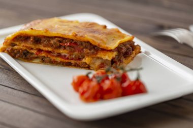 Beyaz tabakta servis edilen peynirle kaplı lezzetli bir lazanya..  