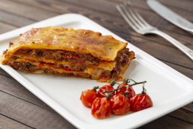 Beyaz tabakta servis edilen peynirle kaplı lezzetli bir lazanya..  