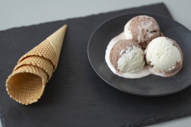 Çikolatalı ve vanilyalı dondurma, gözleme koniler, taş koyu arka plan