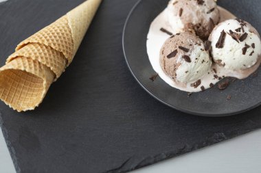 Çikolatalı ve vanilyalı dondurma, gözleme koniler, taş koyu arka plan