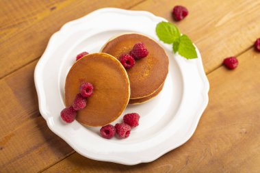 Ahududu ve ahşap zemin üzerine nane ile küçük gözleme