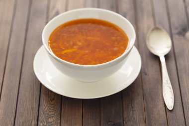 Sebze ve otlar ahşap bir masa üzerinde beyaz bir kase tavuk çorbası