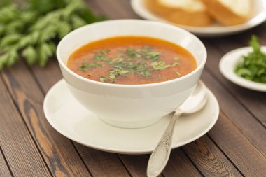 Sebze ve otlar ahşap bir masa üzerinde beyaz bir kase tavuk çorbası