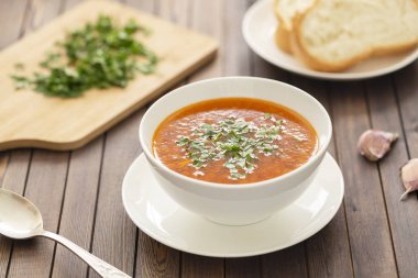 Sebze ve otlar ahşap bir masa üzerinde beyaz bir kase tavuk çorbası