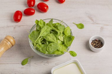 Taze ıspanak yaprakları, domates ve hafif bir arka plan üzerinde diğer salata malzemeleri