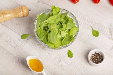 Taze ıspanak yaprakları, domates ve hafif bir arka plan üzerinde diğer salata malzemeleri