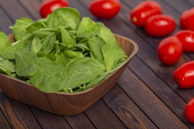 Taze ıspanak yaprakları, beyaz peynir, domates ve koyu ahşap bir masa üzerinde baharat