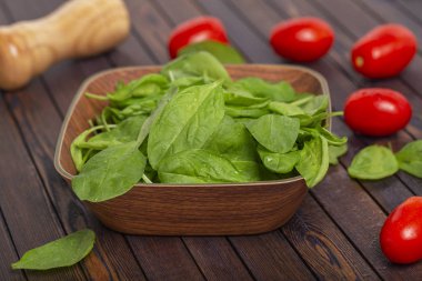 Taze ıspanak yaprakları, beyaz peynir, domates ve koyu ahşap bir masa üzerinde baharat