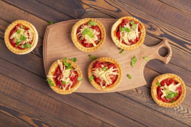 Mini pizza salam, domates, peynir ahşap arka plan üzerinde. Lezzetli meze, tartı. 