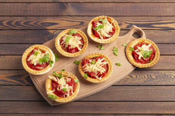 Mini pizza salam, domates, peynir ahşap arka plan üzerinde. Lezzetli meze, tartı. 
