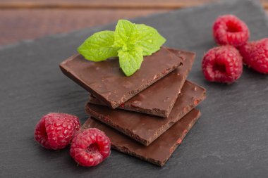 Çikolata parçalarını Kuru ahududu ve taze ahududu kayrak bir plaka üzerinde bir nane yaprağı ile. Yakın çekim.