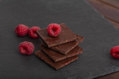 Yapılı-içinde kırmızı ahududu meyveleri ile çikolata bar yığını. Taze ahududu ve çikolata ahşap arka plan üzerinde.