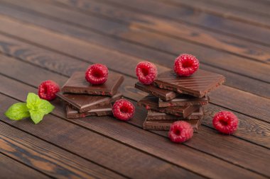 Yapılı-içinde kırmızı ahududu meyveleri ile çikolata bar yığını. Taze ahududu ve çikolata ahşap arka plan üzerinde.