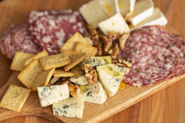 Farklı aperatifler ve mezeler karışımı. Dilim salam, kraker, Fransız camambert peyniri ile mavi küf bal ile ve ahşap zemin üzerine ceviz fındık.