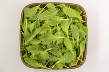 Beyaz arka plan üzerinde izole bir kase taze roka salatası. Üstten görünüm