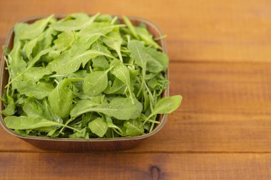 Ahşap arka plan üzerinde bir kase taze roka salatası