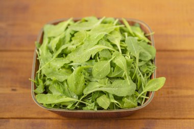 Ahşap arka plan üzerinde bir kase taze roka salatası