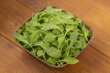 Ahşap arka plan üzerinde bir kase taze roka salatası