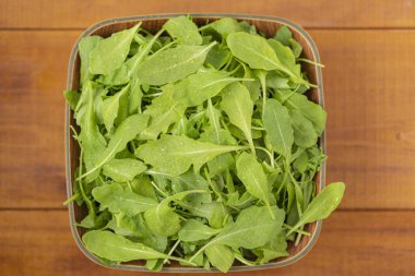 Ahşap arka plan üzerinde bir kase taze roka salatası