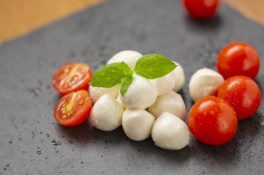 Mozzarella peyniri domates, roka ve baharatlar ile kayrak bir tabakta servis edilir