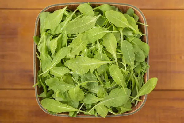 Ahşap arka plan üzerinde bir kase taze roka salatası