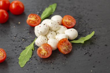 Mozzarella peyniri domates, roka ve baharatlar ile kayrak bir tabakta servis edilir