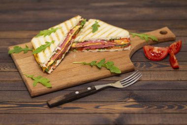 Jambon, peynir, domates ve roka salatası karanlık bir arka plan üzerinde ızgara sandviç. Lezzetli kahvaltı.