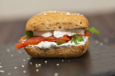 Sandviç ile tahıl ekmek, karanlık bir arka plan üzerinde füme somon ve krem peynir.