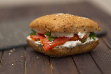 Sandviç ile tahıl ekmek, karanlık bir arka plan üzerinde füme somon ve krem peynir.