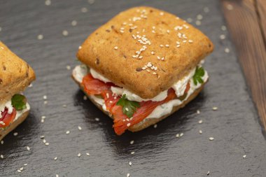 Sandviç ile tahıl ekmek, karanlık bir arka plan üzerinde füme somon ve krem peynir.