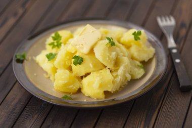 Taze ot ve ahşap bir masa üzerinde bir kasede yağ ile haşlanmış patates