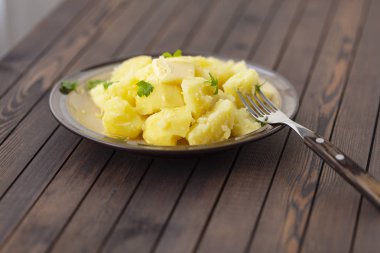 Taze ot ve ahşap bir masa üzerinde bir kasede yağ ile haşlanmış patates