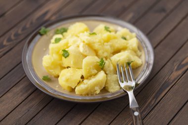 Taze ot ve ahşap bir masa üzerinde bir kasede yağ ile haşlanmış patates