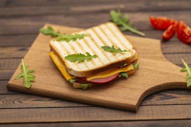 Jambon, peynir, domates ve roka salatası karanlık bir arka plan üzerinde ızgara sandviç. Lezzetli kahvaltı.