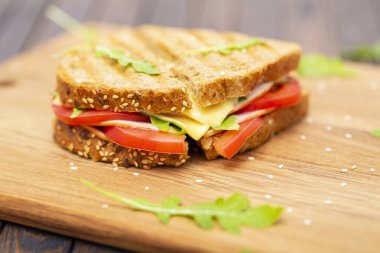 Peynir, jambon, roka ve domates bir ahşap stand ile sandviç. Yakın çekim