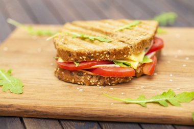 Peynir, jambon, roka ve domates bir ahşap stand ile sandviç. Yakın çekim