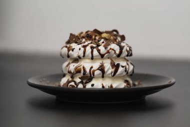 Beze tatlısı Pavlova pasta siyah arka plan üzerine çikolata şurubu ile