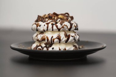 Beze tatlısı Pavlova pasta siyah arka plan üzerine çikolata şurubu ile