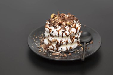 Beze tatlısı Pavlova pasta siyah arka plan üzerine çikolata şurubu ile