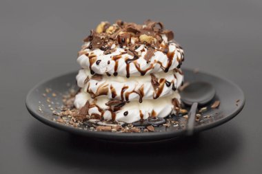 Beze tatlısı Pavlova pasta siyah arka plan üzerine çikolata şurubu ile