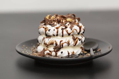 Beze tatlısı Pavlova pasta siyah arka plan üzerine çikolata şurubu ile