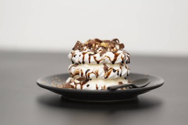 Beze tatlısı Pavlova pasta siyah arka plan üzerine çikolata şurubu ile