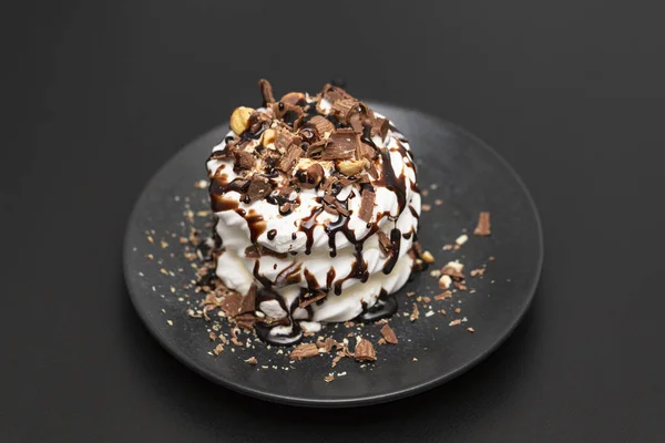 Meringue dessert Pavlova cake with chocolate syrup on black background
