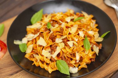 Bolognese makarna. Tagliatelle mantarlı kıyma, domates sosu, fesleğen ve koyu ahşap arka plan üzerinde siyah bir plaka üzerinde Parmesan.