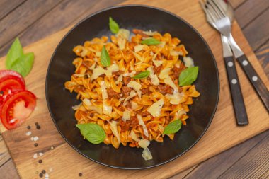 Bolognese makarna. Tagliatelle mantarlı kıyma, domates sosu, fesleğen ve koyu ahşap arka plan üzerinde siyah bir plaka üzerinde Parmesan.