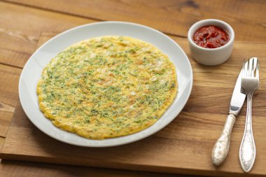 Otlar ile lezzetli omlet. Kahvaltıda omlet. Rendelenmiş peynir ve otlar ile omlet. Kahvaltı için yumurta çanak.