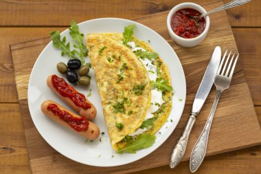 Otlu omlet, yumuşak peynir, ızgara sosis ve domates sosu. Nefis kahvaltı.