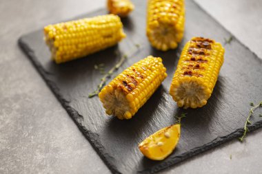 Izgarada mısır ateşe ızgara. Karanlık bir taş masanın üzerine.