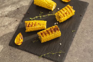 Izgarada mısır ateşe ızgara. Karanlık bir taş masanın üzerine.